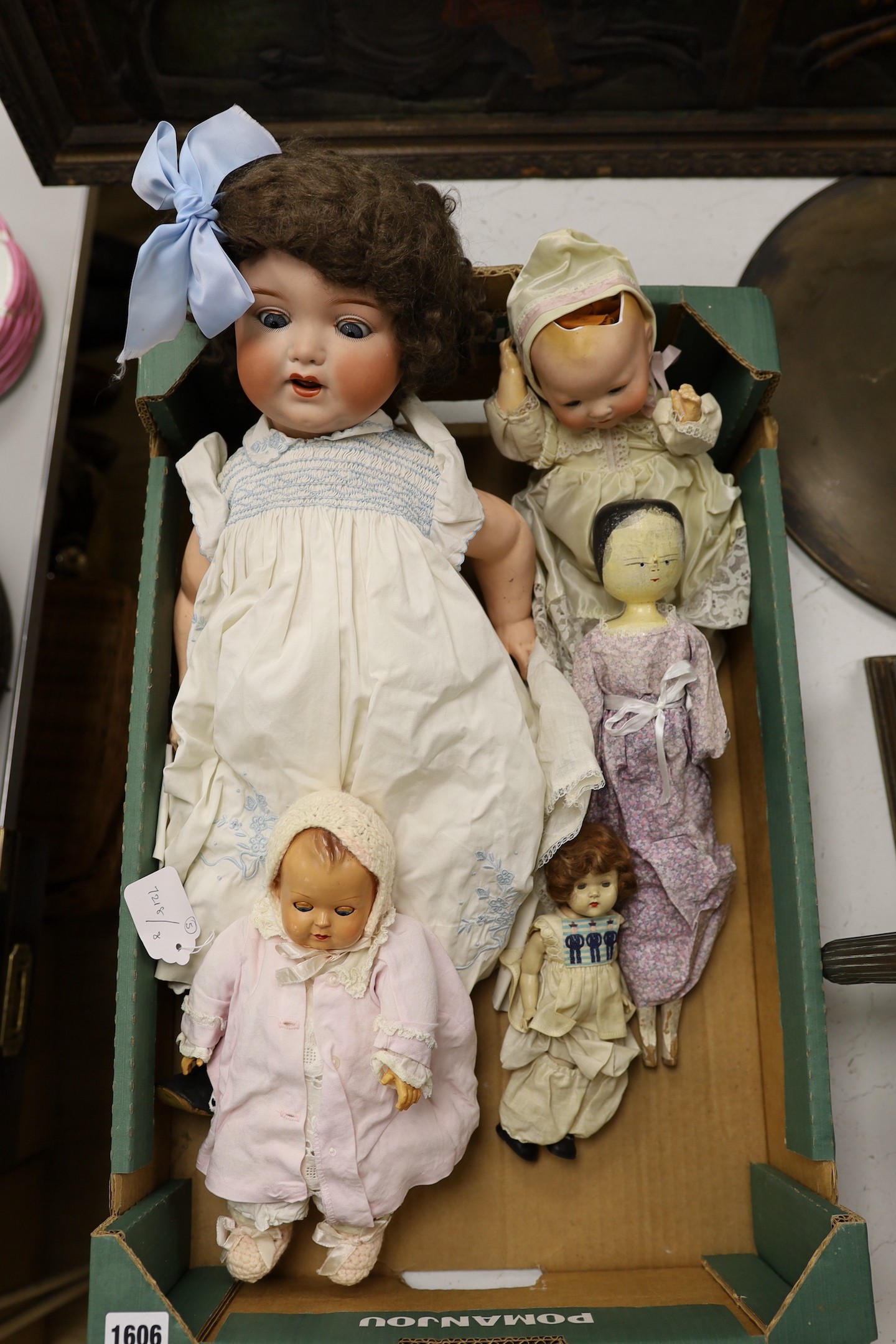 An Armand Marseille open mouthed bisque headed doll, another smaller bisque headed doll, a peg doll and two celluloid dolls